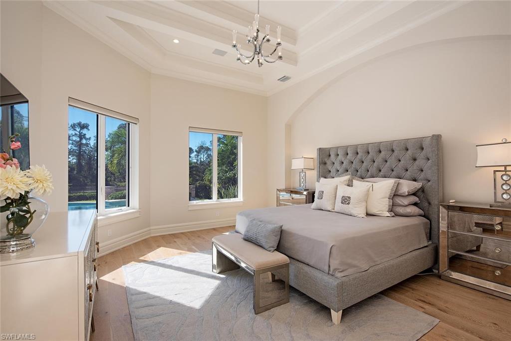 16044 Trebbio Way Naples, FL 34110 - Photo 9 of 33 a bedroom with a large bed and a chandelier