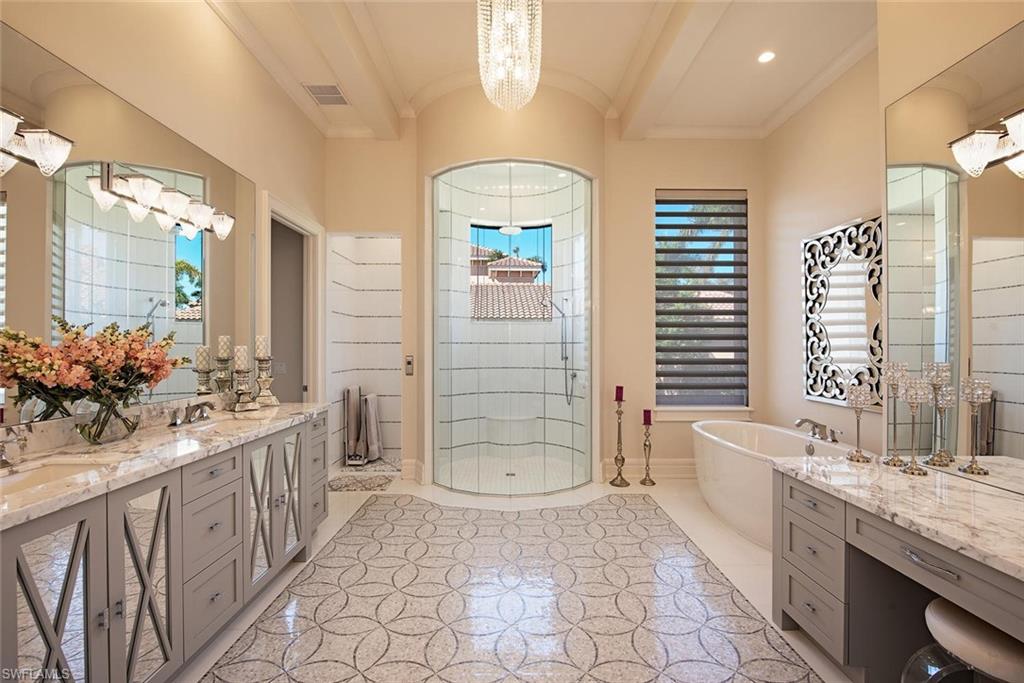16044 Trebbio Way Naples, FL 34110 - Photo 10 of 33 a bathroom with a double vanity sink a large mirror a bathtub and next to a window