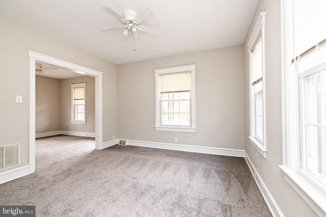 an empty room with windows and ceiling fan