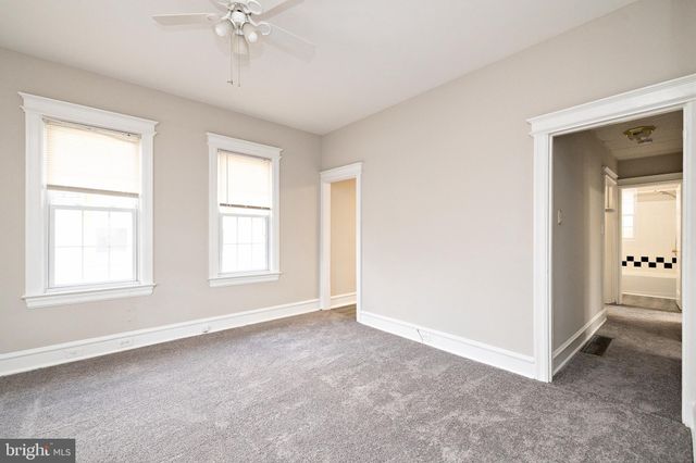 an empty room with chandelier fan and windows