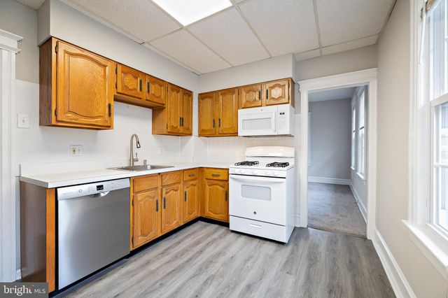 a kitchen with stainless steel appliances granite countertop a sink cabinets and wooden floor