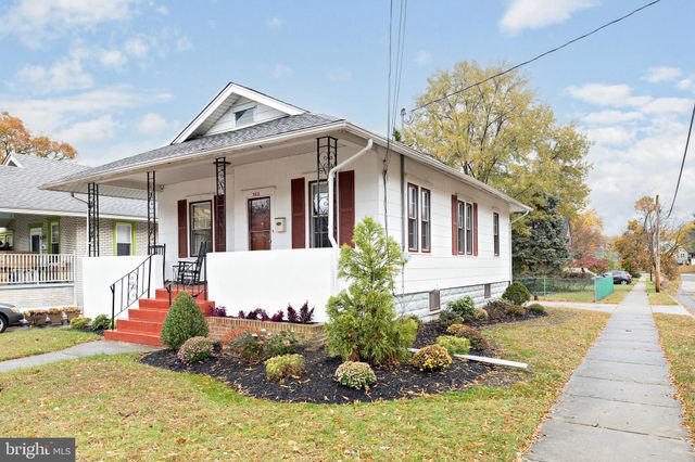 a view of a white house with a yard and potted plants