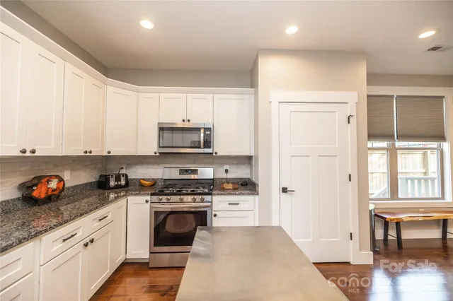 a kitchen with stainless steel appliances granite countertop a stove a sink and a refrigerator
