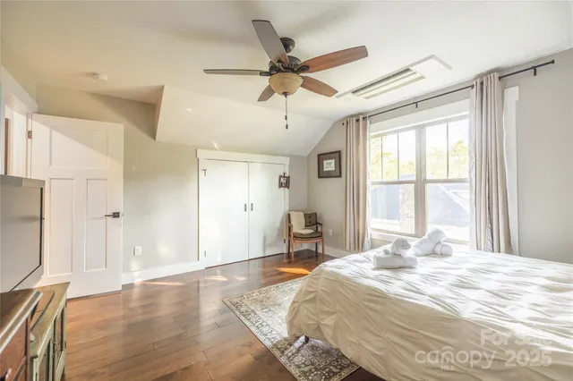 a bedroom with a bed and window with wooden floor