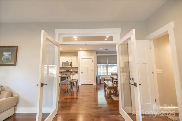 a view of a hallway with wooden floor windows and a living room