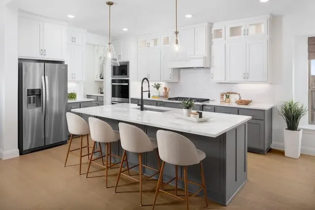 a kitchen with stainless steel appliances granite countertop a sink a stove a refrigerator and white cabinets with wooden floor