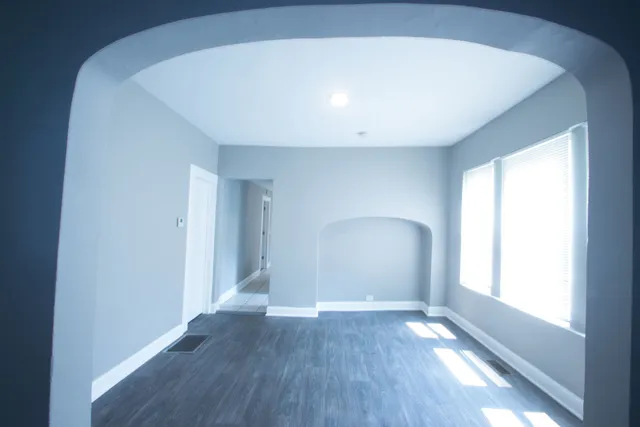a view of empty room with wooden floor and fan
