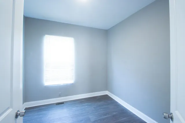 an empty room with wooden floor and a window