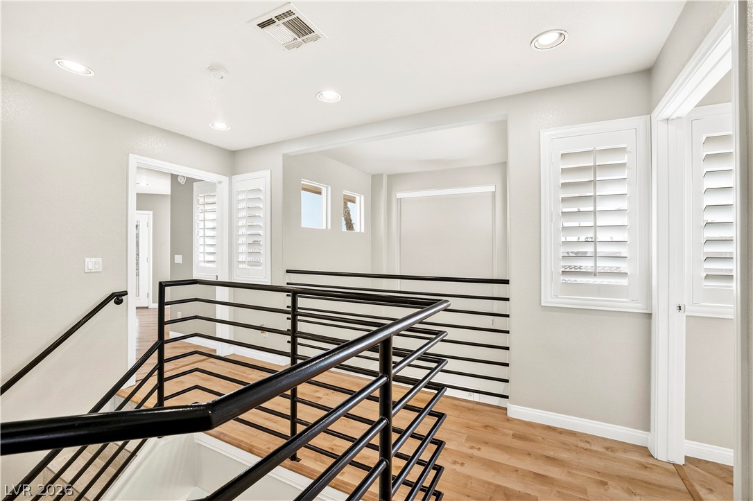 1135 Calico Ridge Drive Henderson, NV 89011 - Photo 44 of 86 Modern interior landing with sleek metal railings and wood-look floors creating an open, inviting atmosphere.