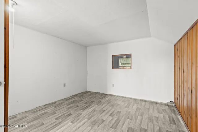 a view of an empty room with wooden floor and closet area