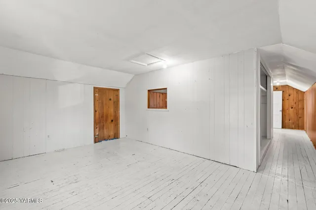a view of an empty room with wooden floor and window