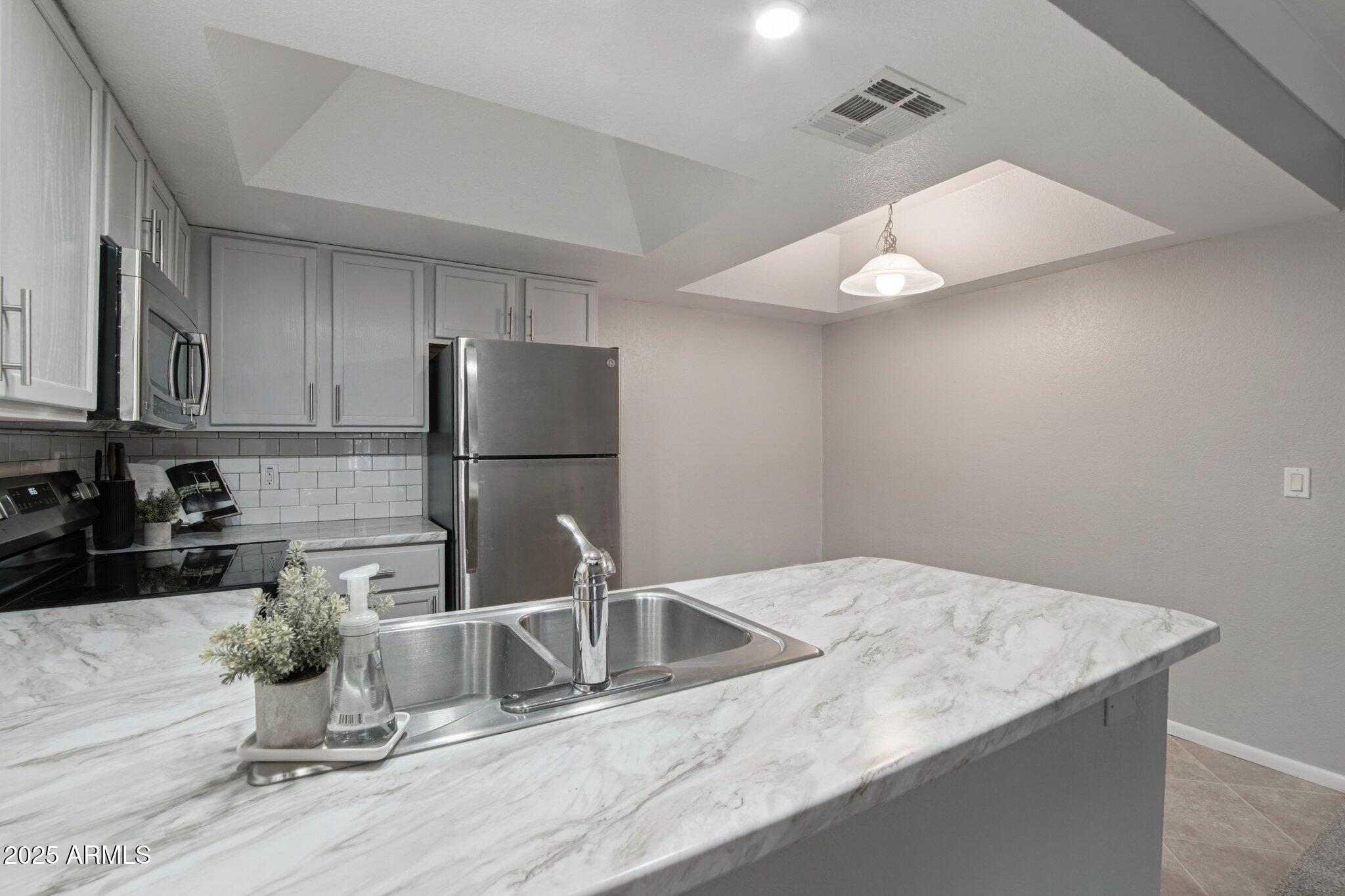 1720 East Thunderbird Road, Unit 2024 Phoenix, AZ 85022 - Photo 5 of 23 a kitchen with a sink a refrigerator and cabinets