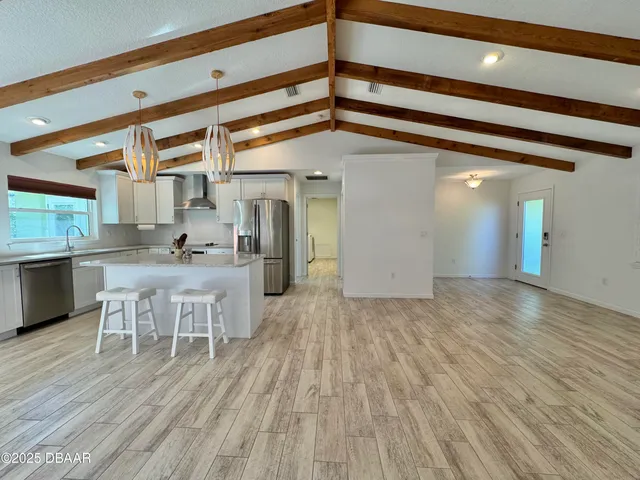 a kitchen with stainless steel appliances a sink a stove a refrigerator cabinets and a window