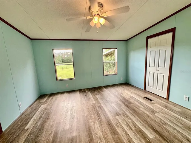 a view of an empty room with a window and wooden floor