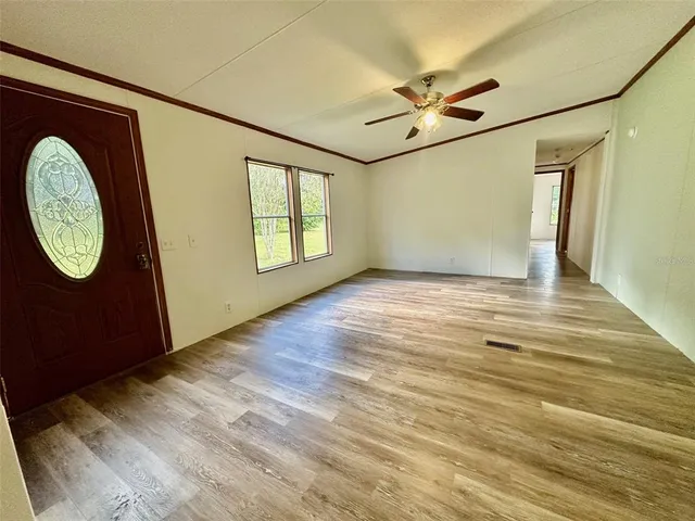a view of an empty room with a window and wooden floor
