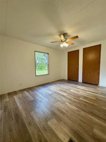 an empty room with windows and ceiling fan