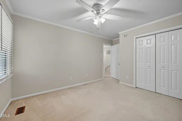 an empty room with a chandelier fan and windows
