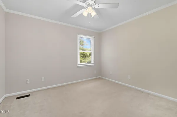 an empty room with a chandelier fan and windows