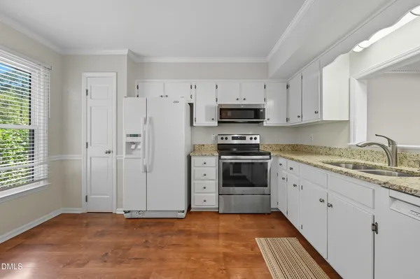 a kitchen with granite countertop a stove a sink and a refrigerator