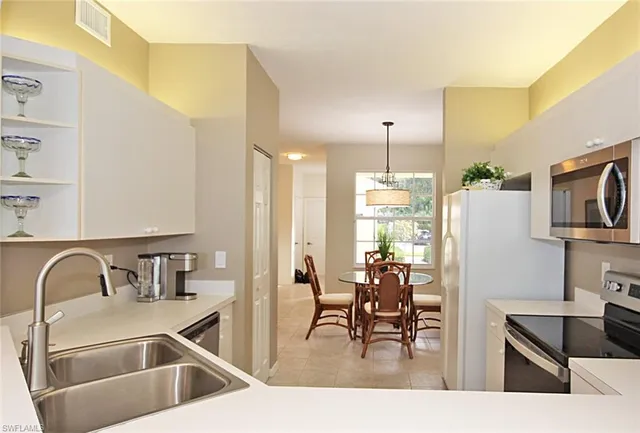 a kitchen with kitchen island a dining table chairs refrigerator and sink