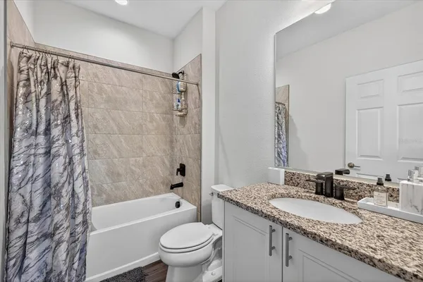 a bathroom with a granite countertop sink a toilet and shower