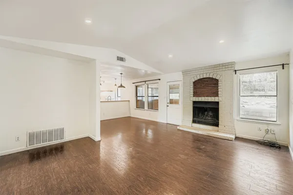an empty room with wooden floor and fireplace
