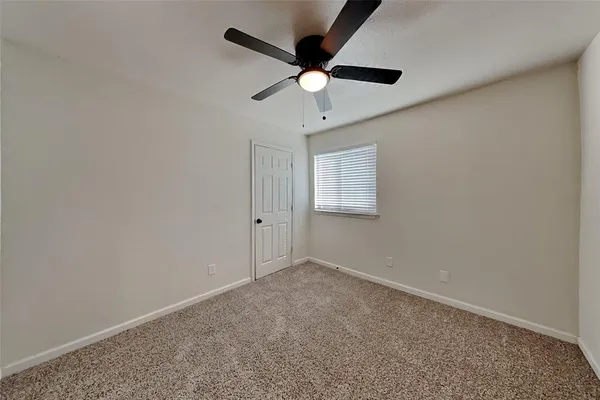 an empty room with a ceiling fan and a window
