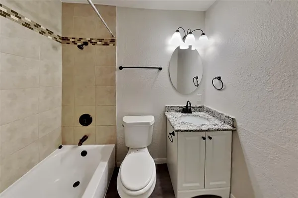 a bathroom with a granite countertop toilet sink and mirror