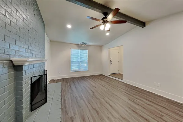 an empty room with wooden floor fireplace and windows