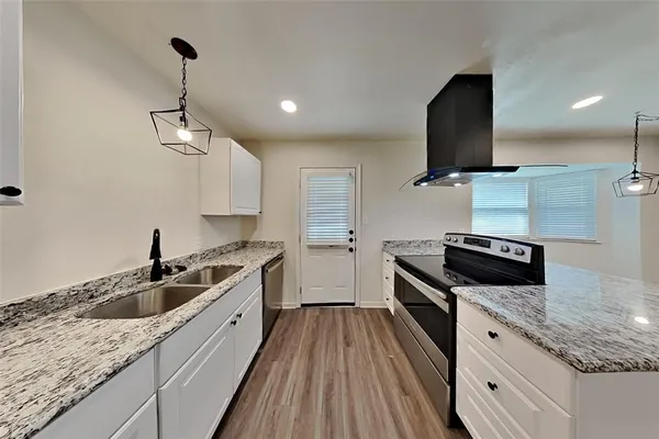 a kitchen with granite countertop stainless steel appliances a sink stove and cabinets
