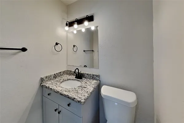 a bathroom with a granite countertop sink a toilet and a mirror