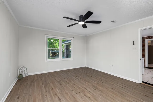 a view of empty room with wooden floor and fan