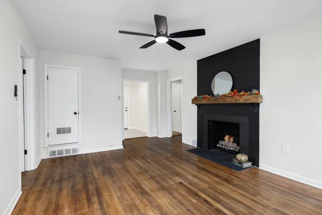 a view of an empty room with wooden floor a fireplace and a window