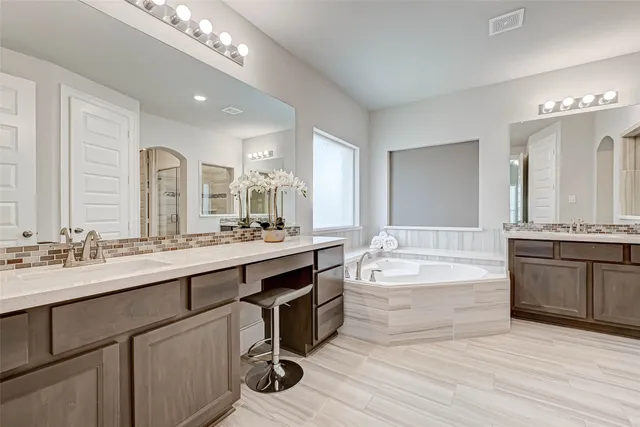 a spacious bathroom with a double vanity sink mirror and bathtub