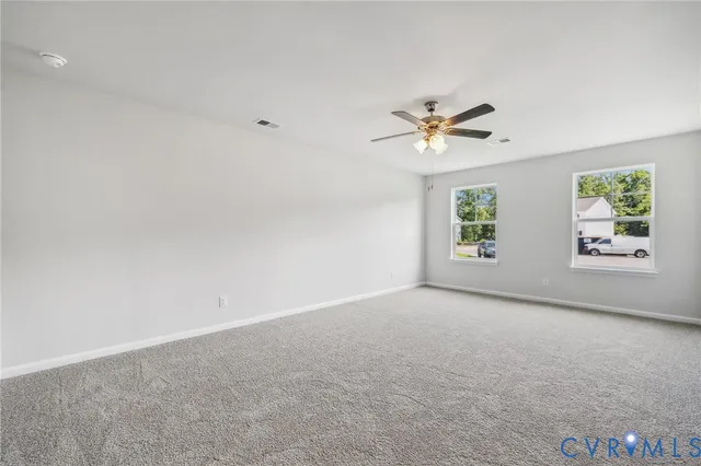an empty room with windows and ceiling fan