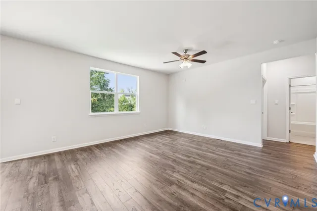 an empty room with wooden floor chandelier fan and windows