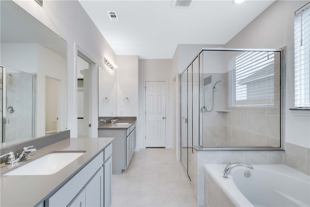 17629 Shafer Drive Pflugerville, TX 78660 - Photo 14 of 35 a bathroom with a granite countertop sink a mirror a bathtub and shower