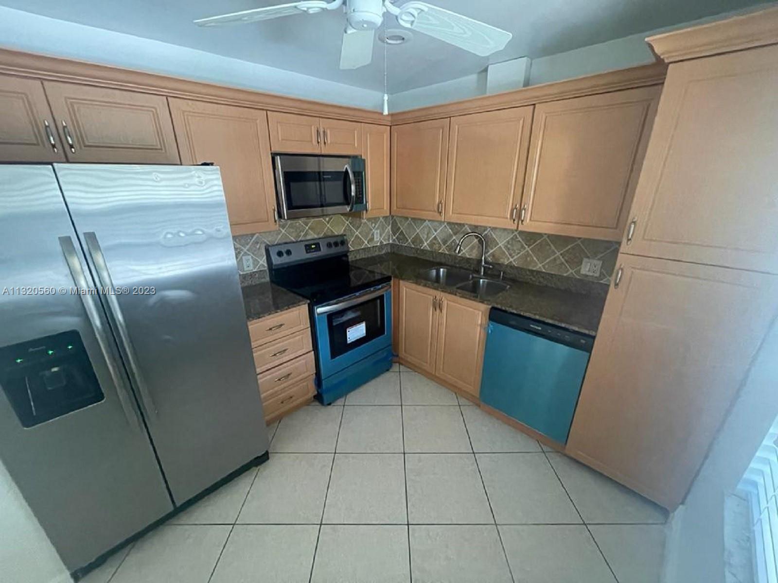 134 South Cypress Road, Unit 421 Pompano Beach, FL 33060 - Photo 4 of 12 a kitchen with granite countertop a refrigerator a microwave a sink and cabinets