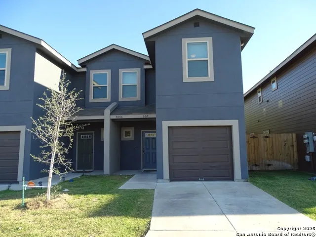a view of a yard in front of a house with a large tree