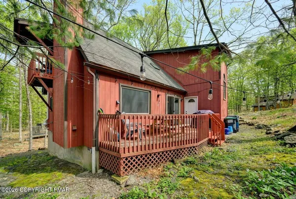 a view of a house with a wooden deck and furniture