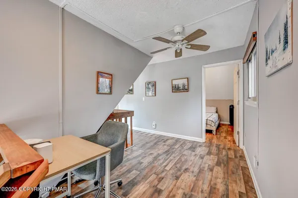 a workspace with wooden floor and ceiling fan