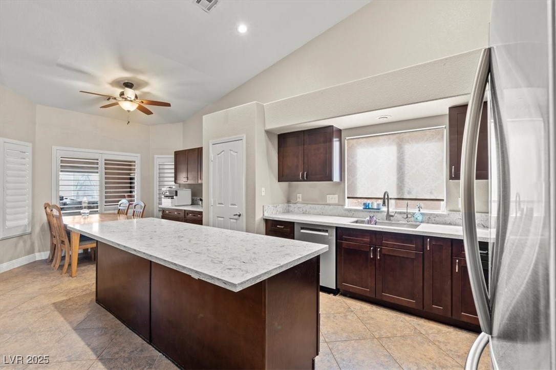 9031 West Viking Road Las Vegas, NV 89147 - Photo 15 of 33 Kitchen featuring a sink, a kitchen island, stainless steel appliances, lofted ceiling, and dark brown cabinets