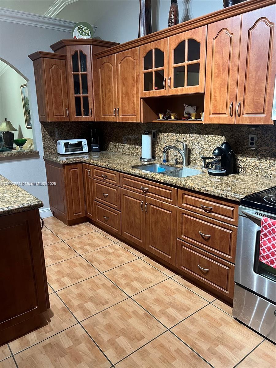 7667 Northwest 182nd Lane, Unit 805 Hialeah, FL 33015 - Photo 4 of 14 a kitchen with stainless steel appliances granite countertop a stove a sink and a microwave