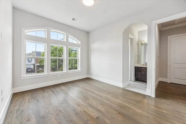 an empty room with wooden floor cabinet and windows