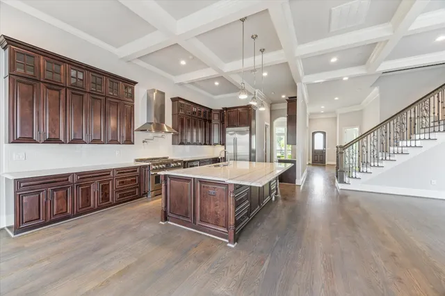 a large kitchen with stainless steel appliances granite countertop a large stove a sink dishwasher and wooden cabinets with wooden floor