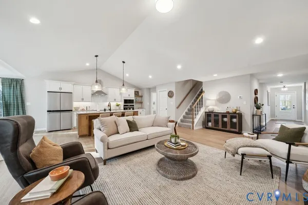 a living room with furniture kitchen view and a wooden floor