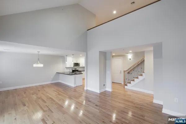 a view of an empty room with wooden floor and windows