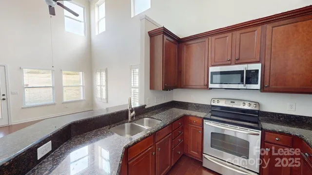 a kitchen with granite countertop a stove sink and microwave