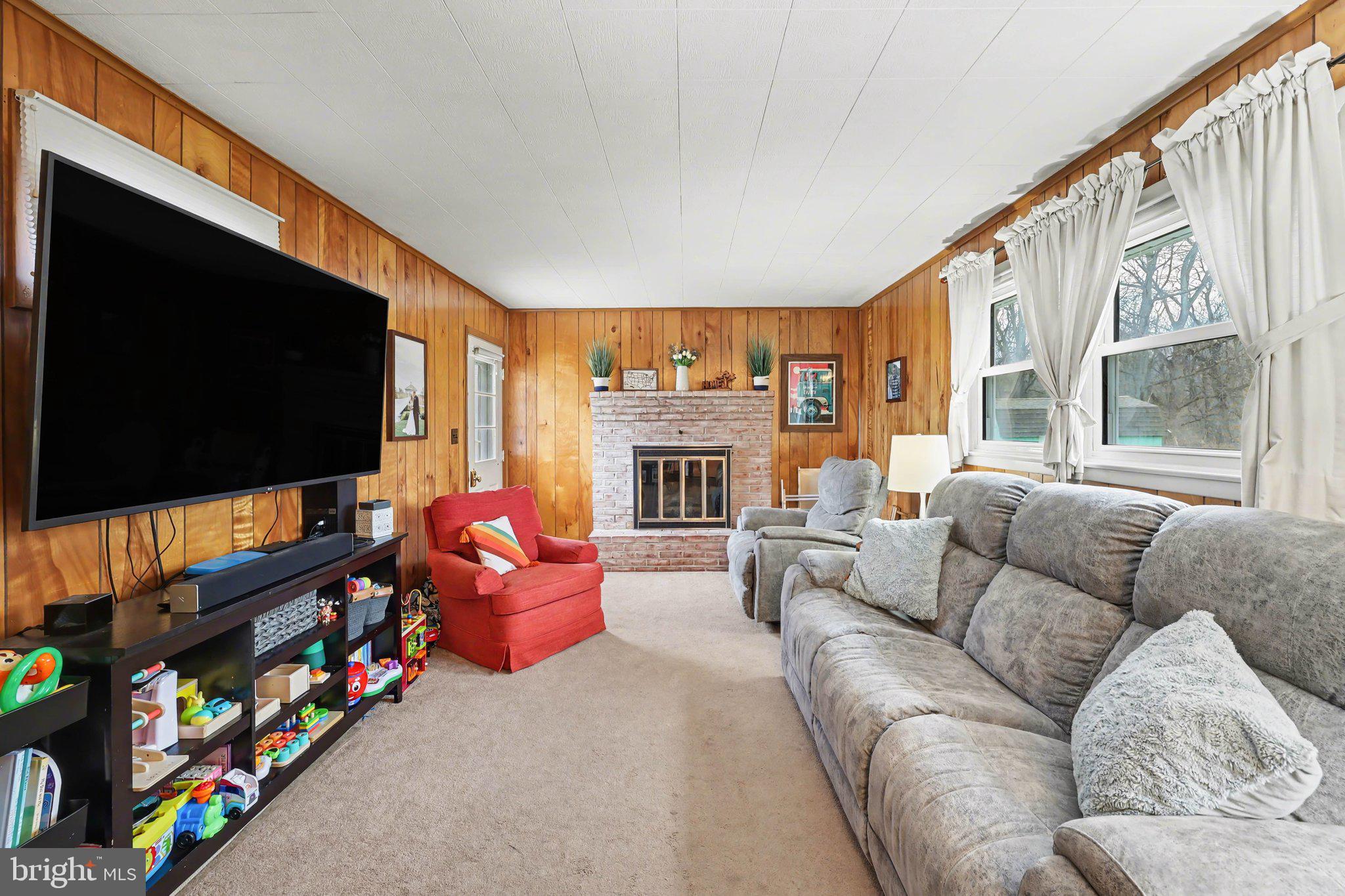 109 Adams Road Carlisle, PA 17015 - Photo 10 of 29 a living room with furniture a flat screen tv and a floor to ceiling window