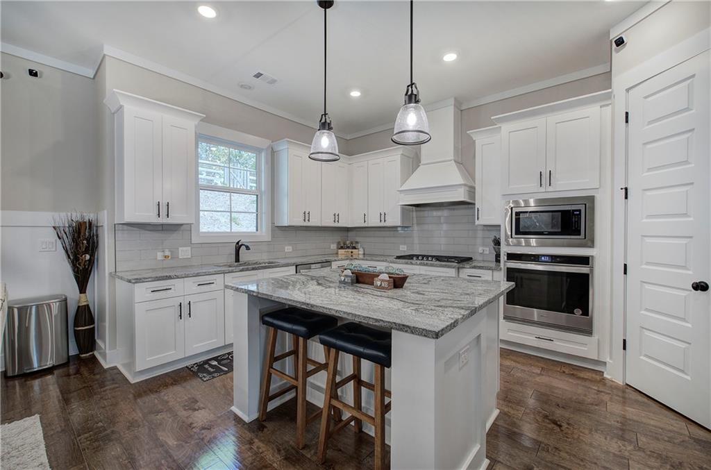 503 London Road Ball Ground, GA 30107 - Photo 11 of 55 a kitchen with a stove a sink a microwave a center island and cabinets